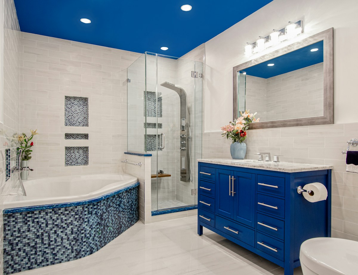 Mavi banyo dolabı ve beyaz seramiklerle tasarlanmış banyo